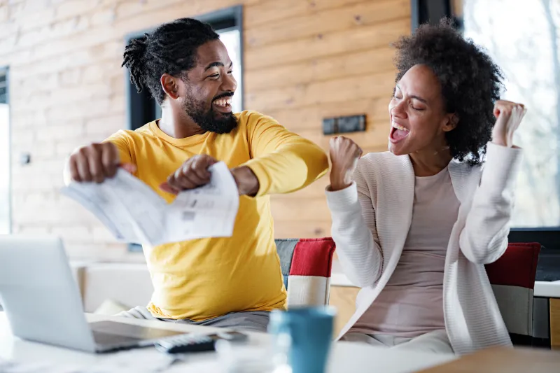 Man and women celebrating as man tears up a credit card bill