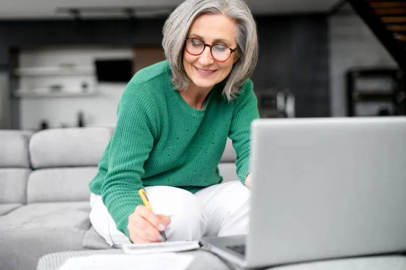 Senior woman wearing a green sweater on her laptop.