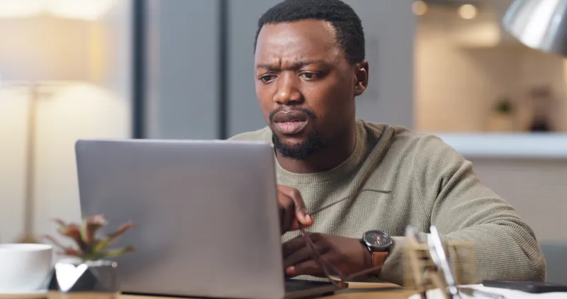 man looking worried at his laptop computer screen