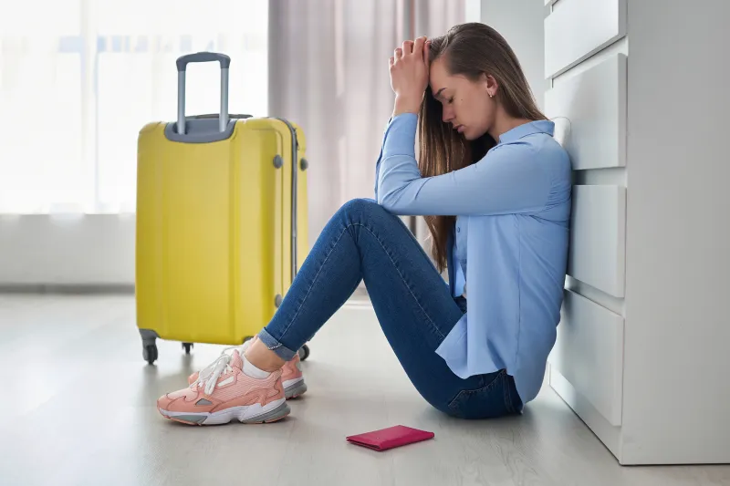 girl leaning on her hands beside her yellow suitcase.