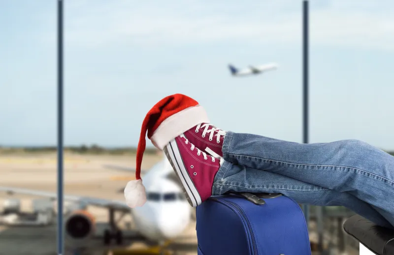 photo of shoes and a santa hat propped op on a suitcase at the airport.