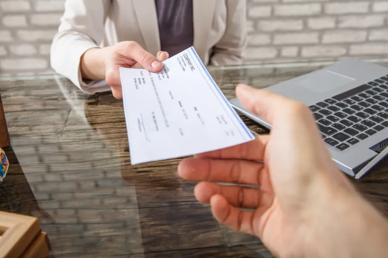 person handing over a check to a bank teller