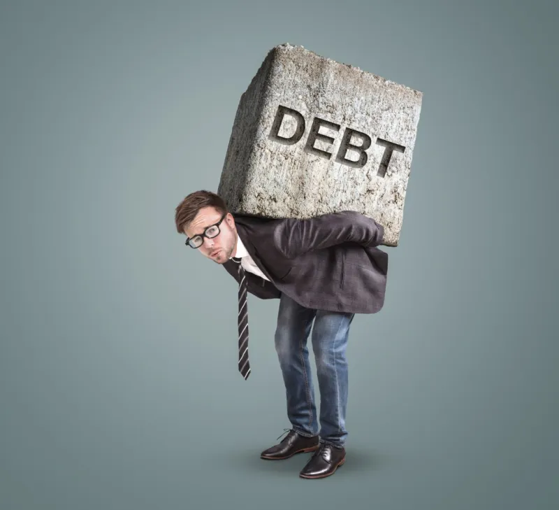 man wearing a suit and glasses with a rock on his back that says DEBT.