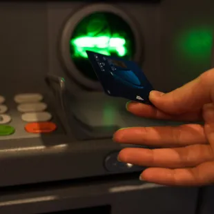 a hand inserting a card into an ATM
