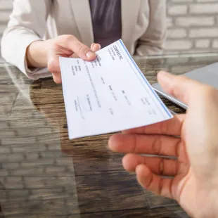 person handing over a check to a bank teller